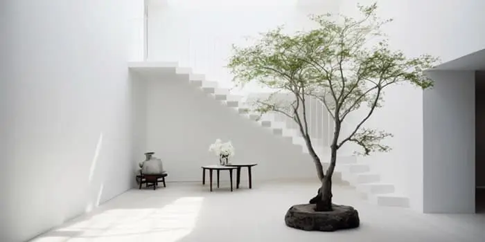 Casa minimalista de dos plantas decorada completamente de blanco con un árbol en el centro