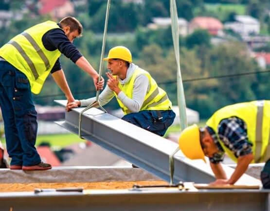 Trabajadores sujetando una viga prefabricada de acero a una grúa Trabajadores sujetando una viga prefabricada de acero a una grúa