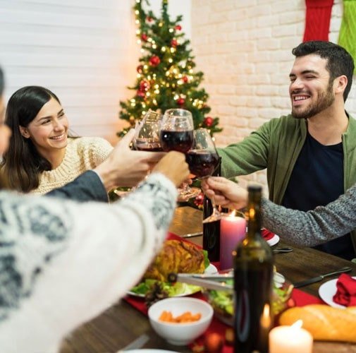 Amigos reunidos dentro de una casa brindando frente al árbol de Navidad Amigos reunidos dentro de una casa brindando frente al árbol de Navidad