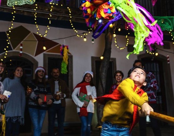Familias mexicanas rompiendo la pinata en las calles de mexico durante una posada Familia compartiendo la cena de nochebuena frente al árbol de Navidad