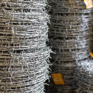 Rollos de alambre de púas acomodados unos sobre otros dentro de una bodega de acero