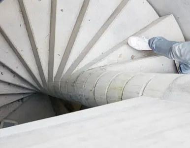 Persona descendiendo por escalera de caracol de concreto Persona descendiendo por escalera de caracol de concreto