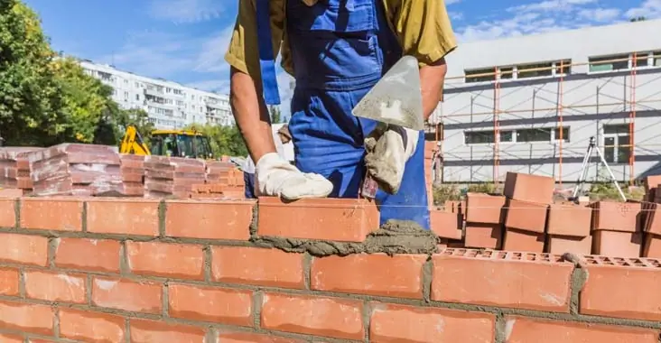 Albañiles levantando un muro de block para crear las cercas perimetrales de una casa Albañiles levantando un muro de block para crear las cercas perimetrales de una casa