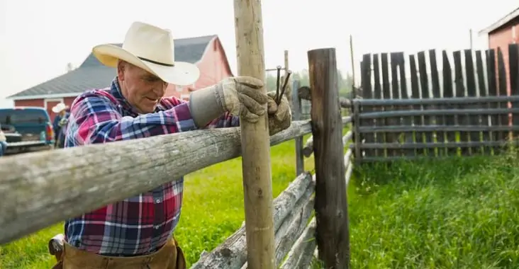 Vaqueros instalando una cerca perimetral para rancho al costado de una casa Vaqueros instalando una cerca perimetral para rancho al costado de una casa