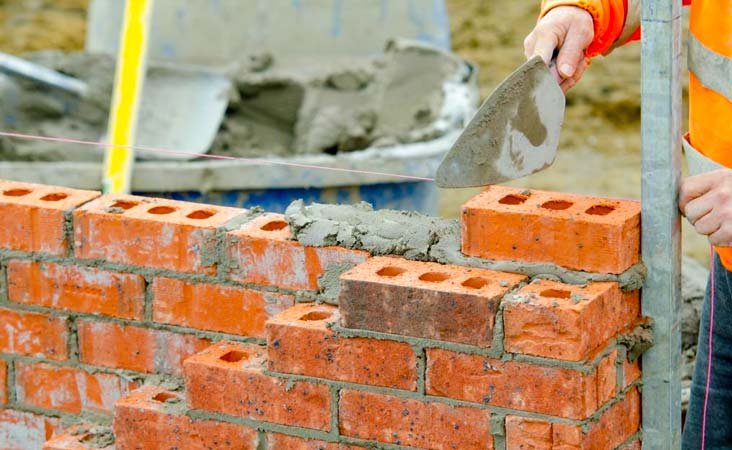 Trabajadores de la construcción levantando un muro de mampostería estructural Trabajadores de la construcción levantando un muro de mampostería estructural