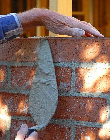 Manos de albañil construyendo una barda con tabiques Manos de albañil construyendo una barda con tabiques
