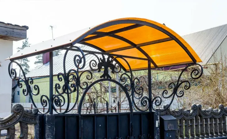 Marquesina de policarbonato celular de color naranja sobre la puerta de entrada de una casa Marquesina de policarbonato celular de color naranja sobre la puerta de entrada de una casa