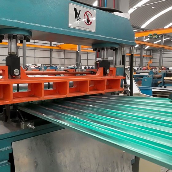 Lámina Tipo Tablero saliendo de la máquina roladora, al fondo una bodega