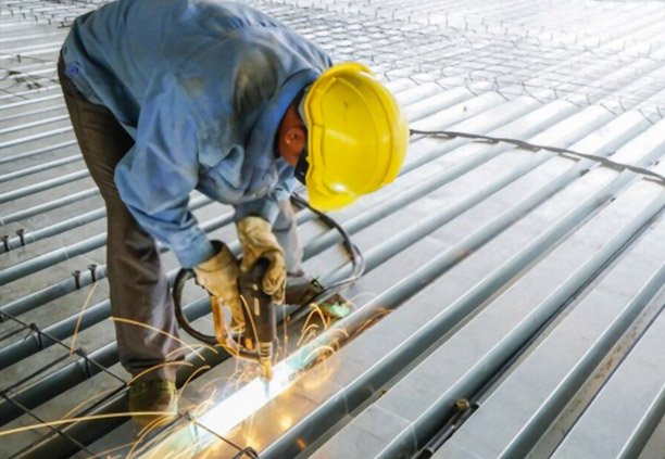 Trabajador instalando una lámina acanalada galvanizada por medio de soldadura en la construcción de una losa metálica