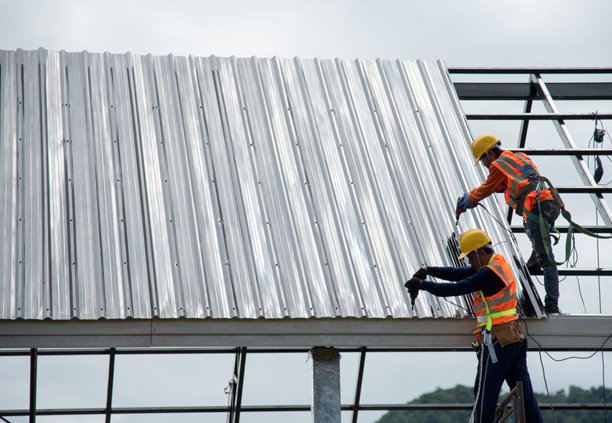 Trabajadores llevando a cabo la instalación de láminas galvanizadas R-72 sobre una estructura metálica para techo