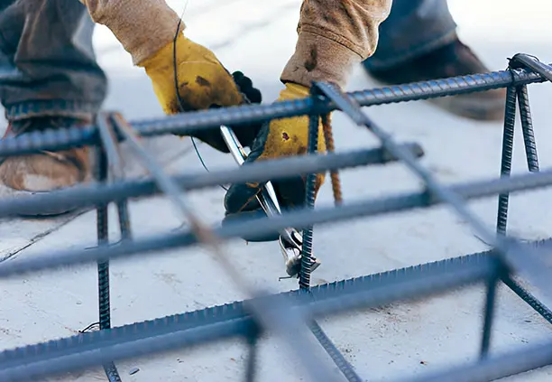 Trabajador asegurando los estribos de una estructura de varillas con un trozo de alambre recocido
