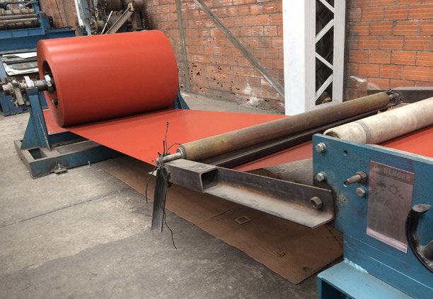 Rollo de Lámina de Acero Pintro de color rojo pasando por una máquina roladora