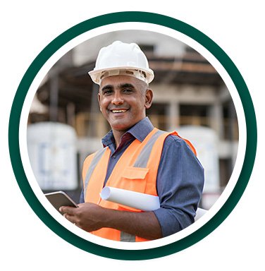 Arquitecto con chaleco de trabajo y casco de seguridad de color blanco frente a una obra en construcción
