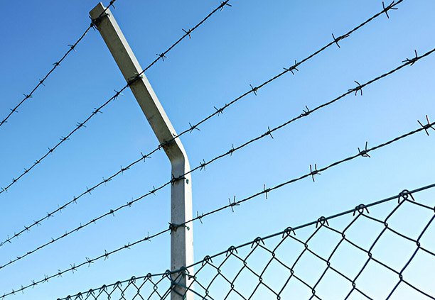 Acercamiento a la instalación de alambre de púas en una valla matálica