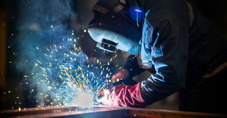 Trabajador realizando soldadura de acero con protección y herramientas hechas con materiales aislantes de electricidad