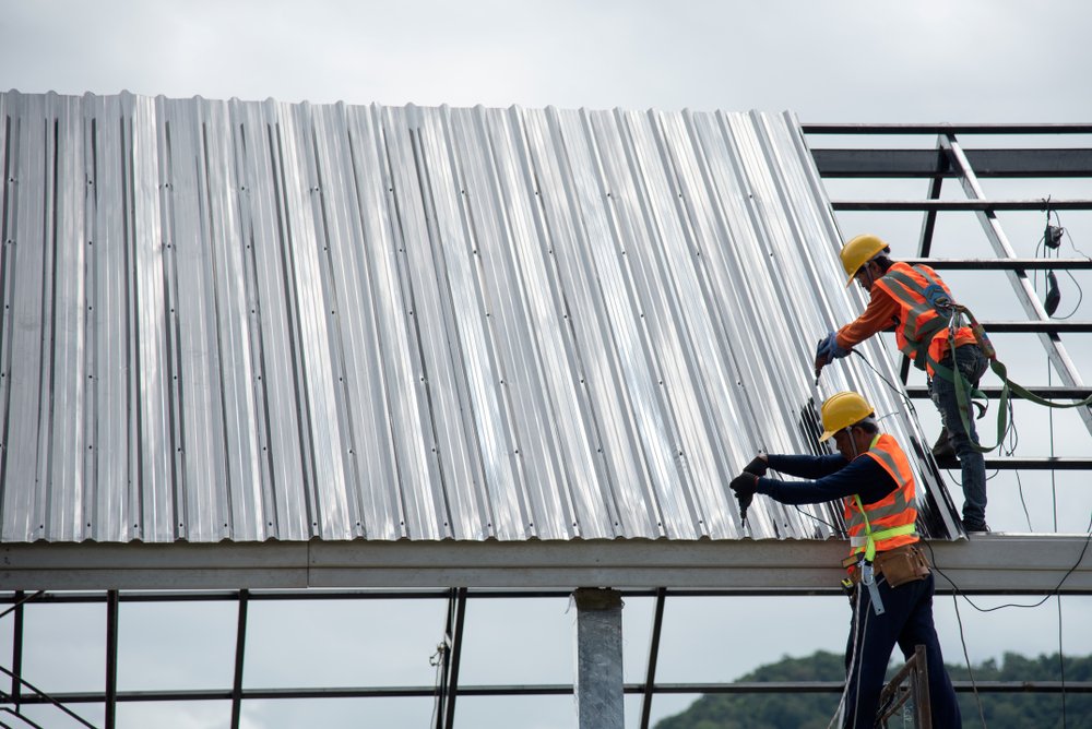 Trabajadores sobre estructura de metal instalando lámina para techo