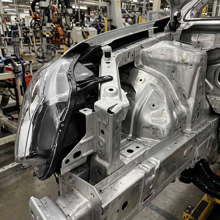 Estructura de carrocería ensamblada con lámina de aluminio en un taller automotriz.